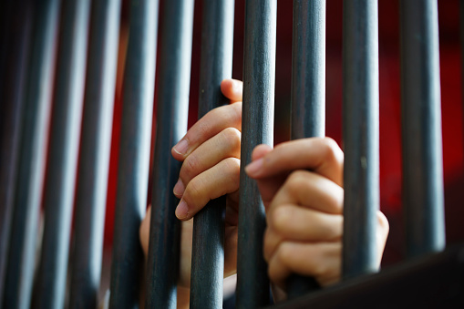 prisoners hands on cell bars