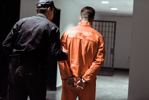 view of prison officer leading prisoner in handcuffs in corridor